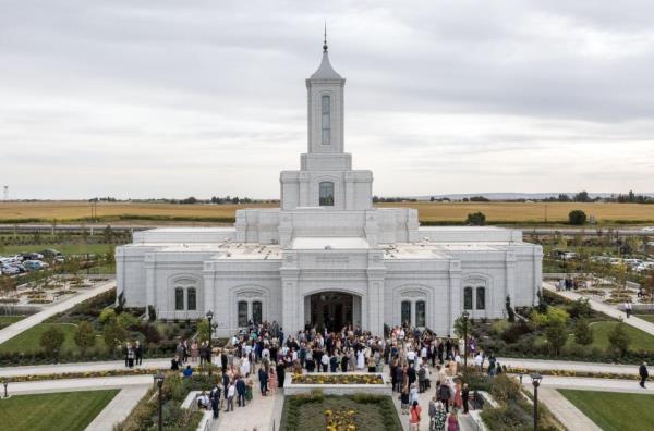 Emily Stewart helps Latter-day Saints put on shoe coverings before a dedication session for the Bentonville Arkansas Temple.