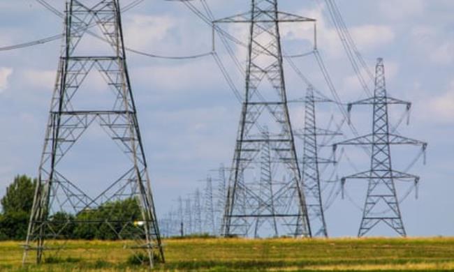 Pylons stretch into the distance across flat fields