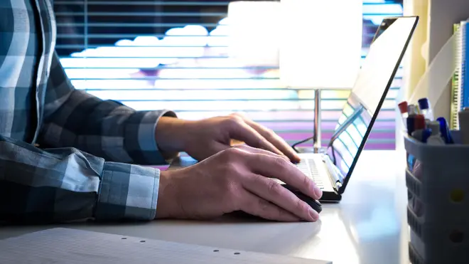 Man using laptop in modern business office with blurred city