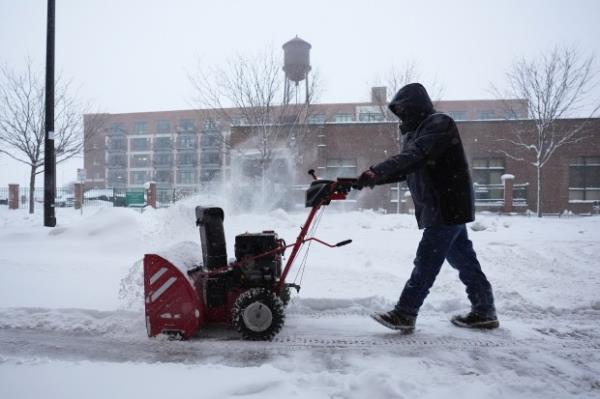 A man clears snow off a sidewalk Friday, Jan. 12, 2024, in Des Moines, Iowa. (Abbie Parr/AP)